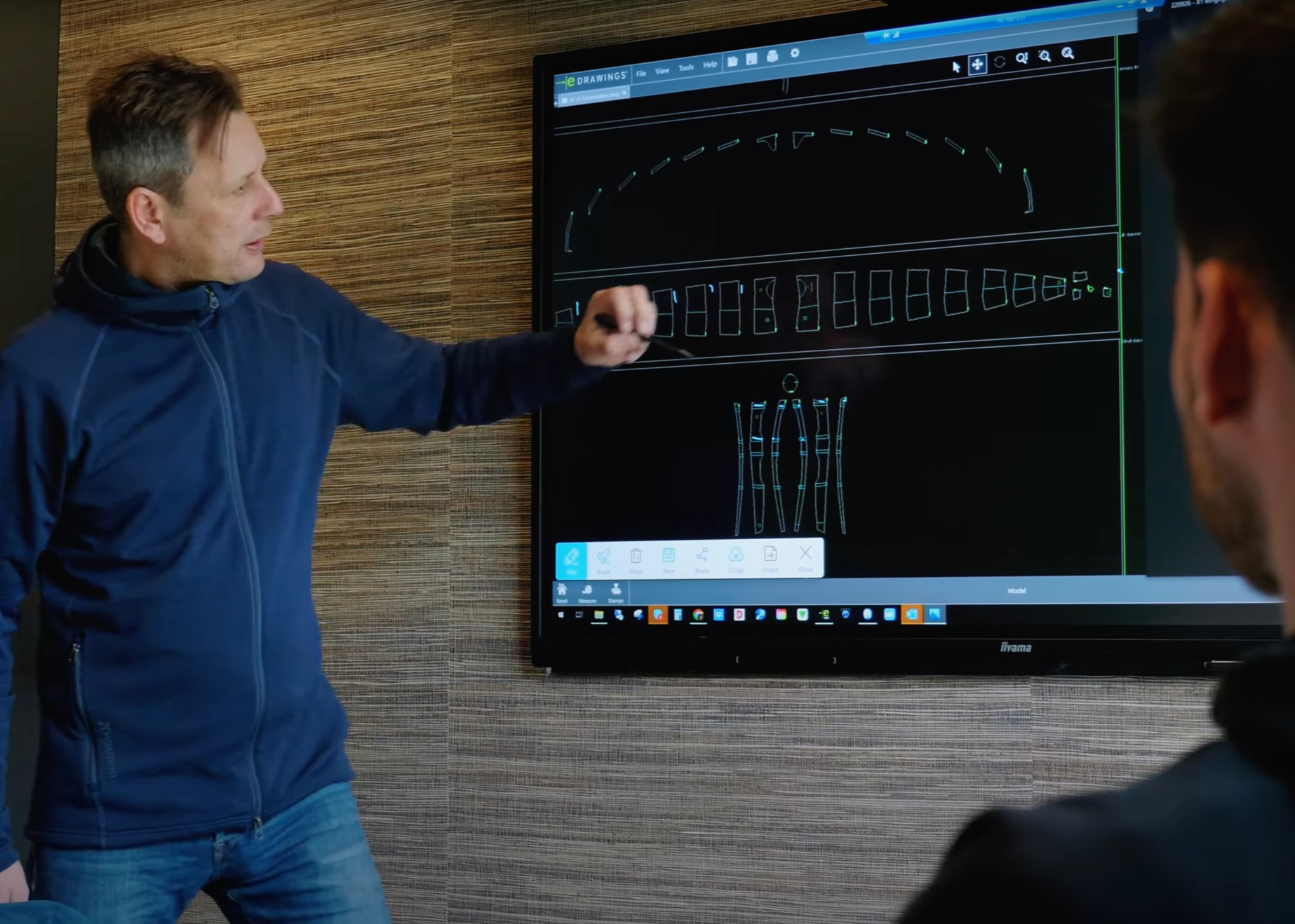 Aery designer explaining wing technical drawings on screen. The CAD software displays precise engineering plans for the Aeryn wing, showing its curved aerodynamic profile at top and detailed panel layouts below. The cross-sectional view at bottom reveals internal baffle design crucial for stability.